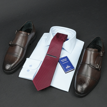 a tie, dress shirt, and dress shoes on a black surface