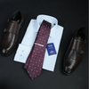 a dress shirt, tie, and dress shoes on a table