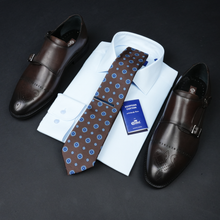 a tie, dress shoes, and a business card on a table