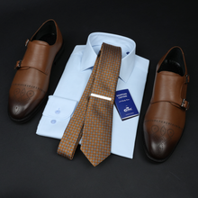 a dress shirt, tie, and dress shoes on a black surface