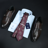 a tie, dress shoes, and a shirt on a table