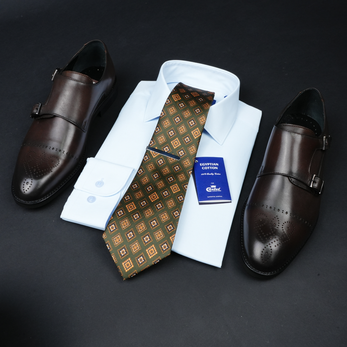 a tie, dress shoes, and a business card on a black surface