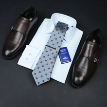 a tie, dress shirt, and dress shoes on a black surface