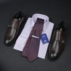 a tie, dress shoes, and a business card on a table